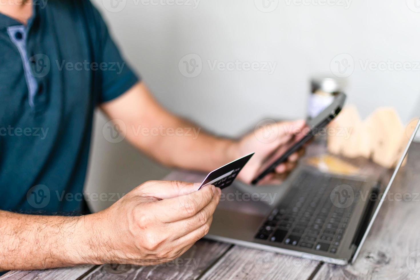 A man's hand holds a credit card for payment online shopping. Concept of financial, money, transfer, phone, copy space, real, estate, budget. Closeup, copy space for design or text. Blurred background photo