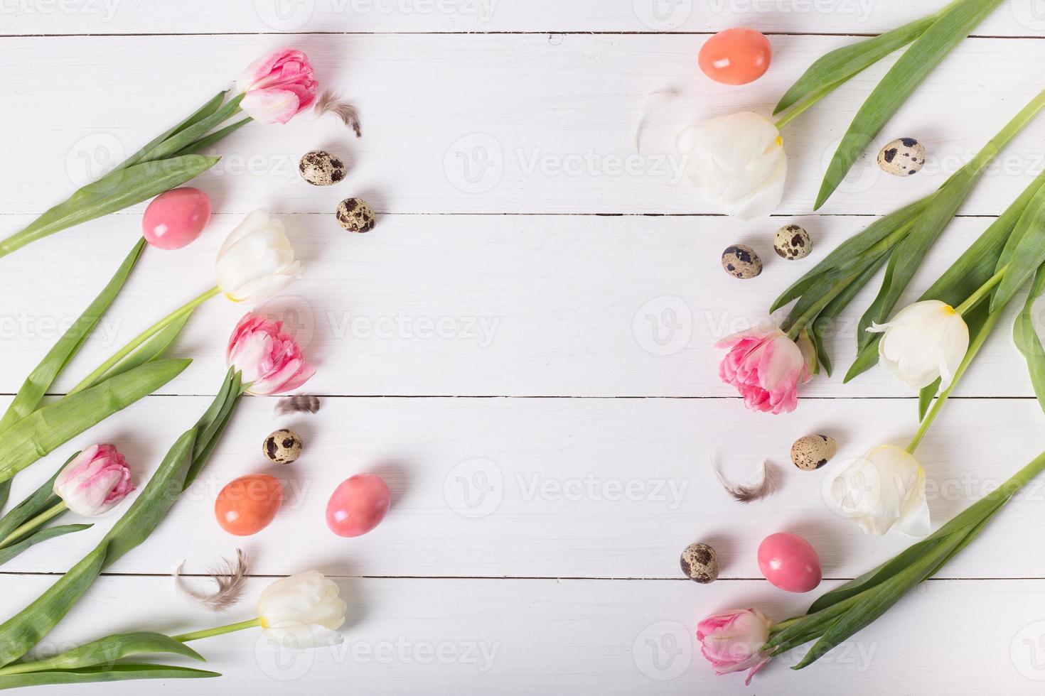 Beautiful pink tulips with colorful quail and chicken eggs in nest on white wooden background. Spring and Easter holiday concept with copy space. photo