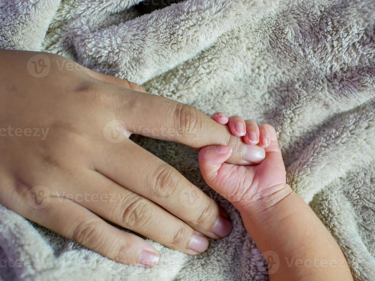 Newborn baby grasping her mother's finger. Concept of baby care, feeling safe, parent love. Selective soft focus. photo