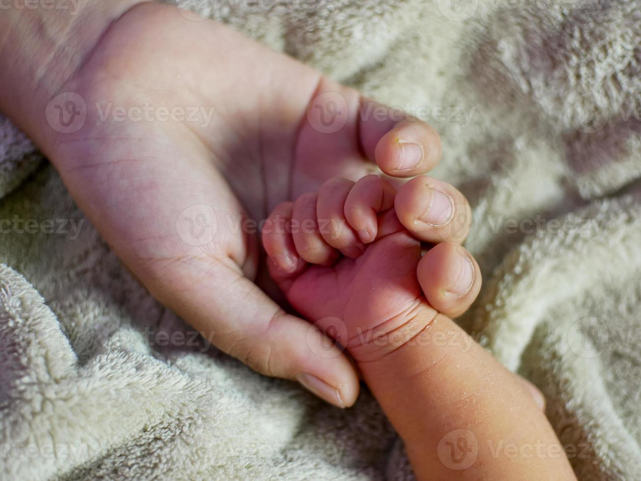 Close up mother hand hold her baby's tiny hand. Concept of child care, feeling safe, parent love. photo