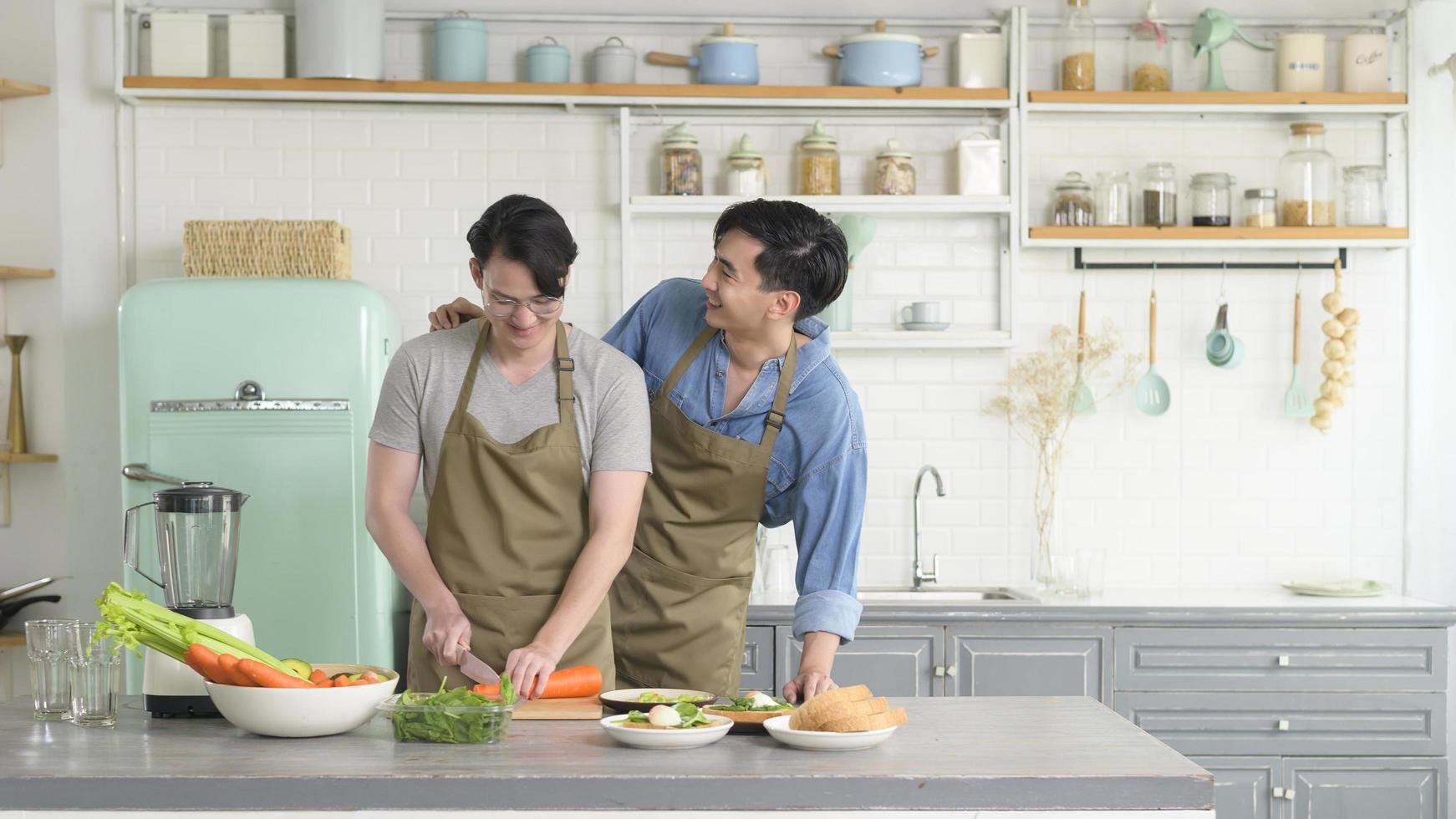 joven pareja gay sonriente cocinando juntos en la cocina en casa, lgbtq y concepto de diversidad. foto