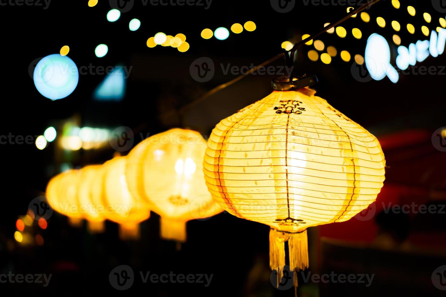 A row of yellow lanterns at night against a blurred background. photo