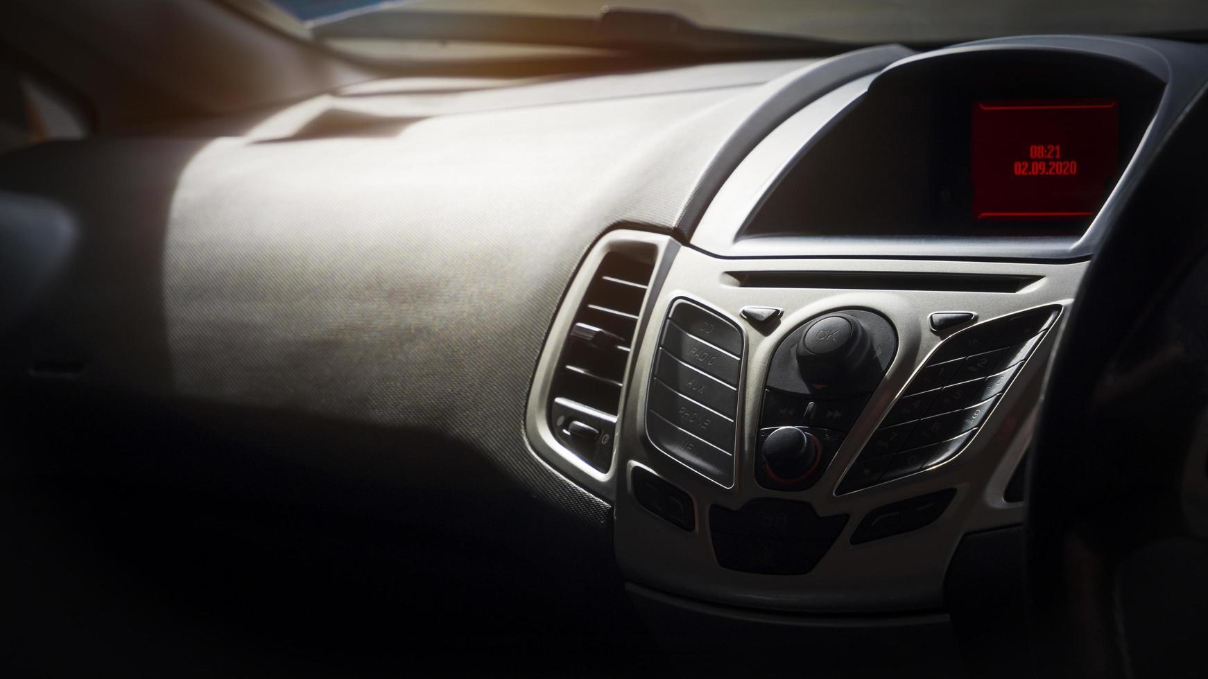 Focus at control panel of assistive devices with air vents and digital date and time dial on black console inside of car photo