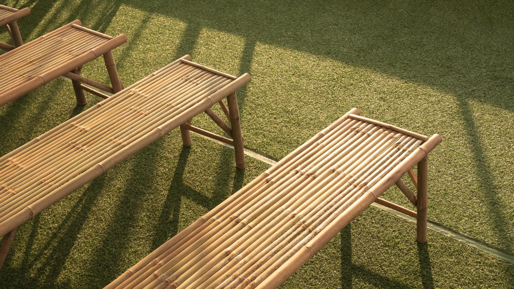 High angle view of bamboo benches on green turf with sunlight and shadow on surface photo