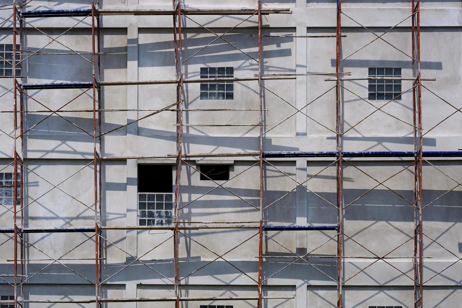 Sunlight and shadow on scaffolding surface outside of high building in construction site photo