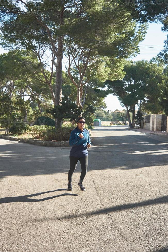 mujer fitness madura, entre 30 y 50 años, corriendo, en la carretera, foto