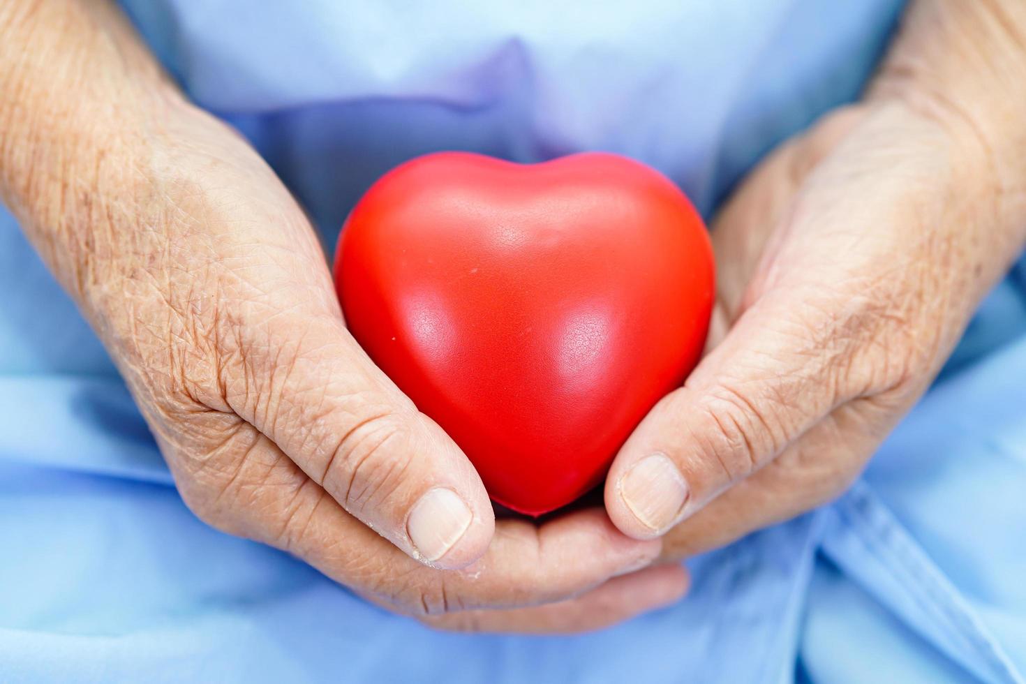 Asian elder senior woman patient holding red heart in hospital. photo