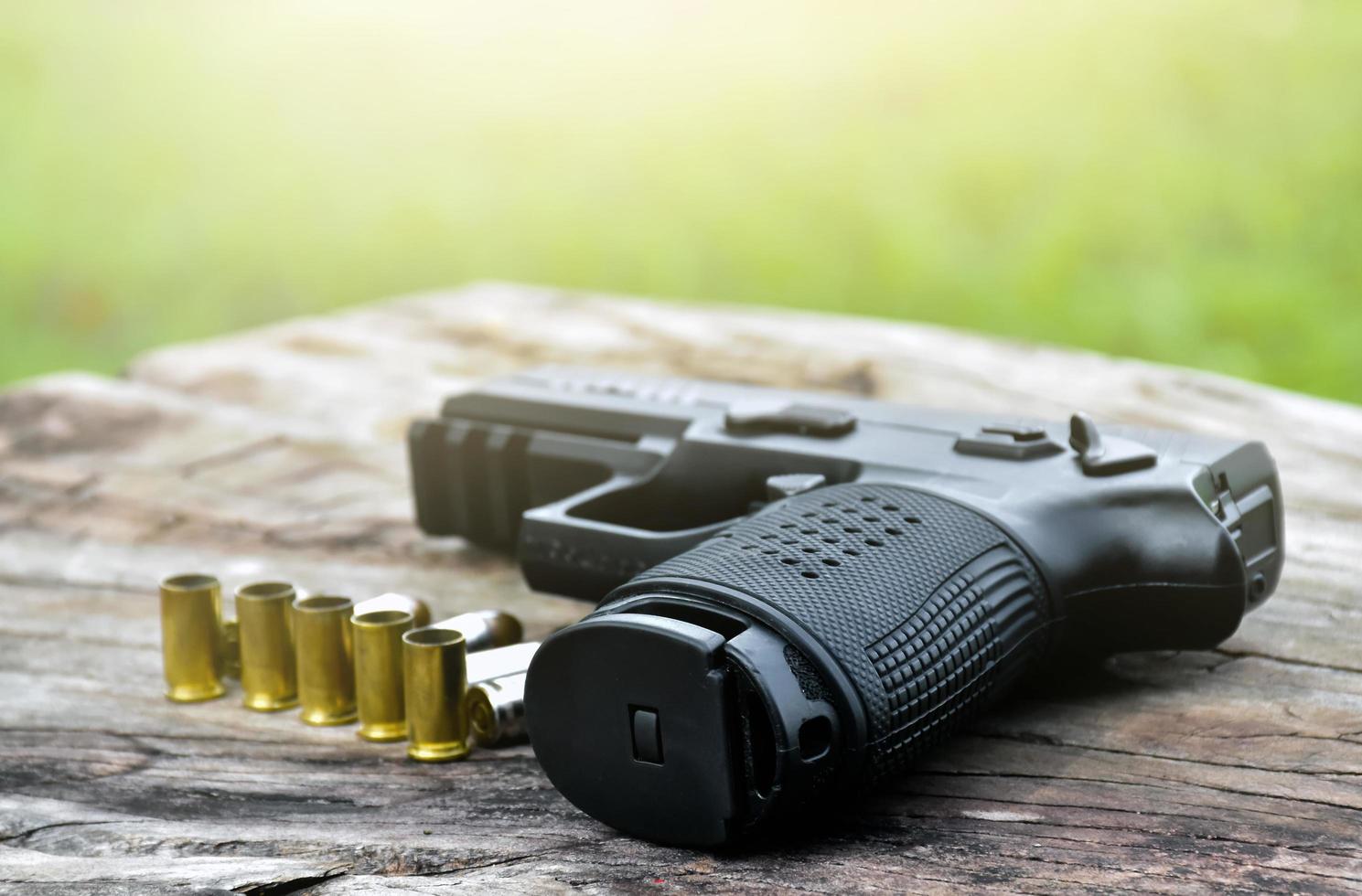 Pistola negra automática de 9 mm y balas sobre una mesa de madera. foto