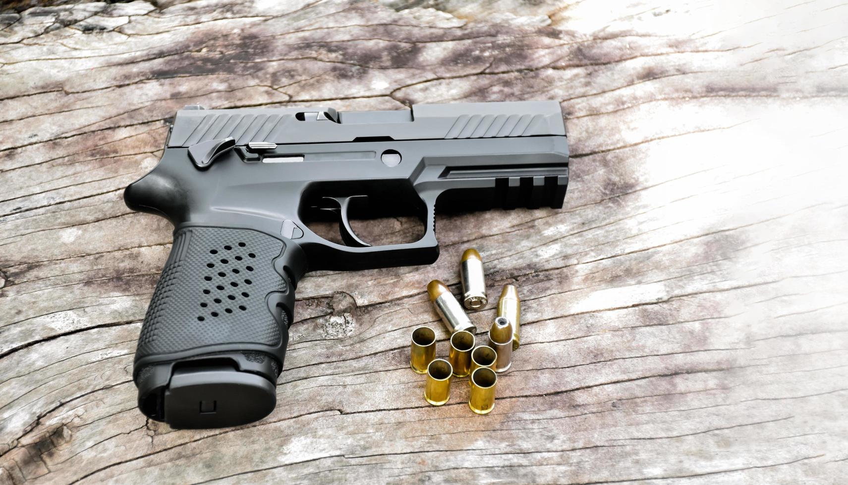 Pistola negra automática de 9 mm y balas sobre una mesa de madera. foto