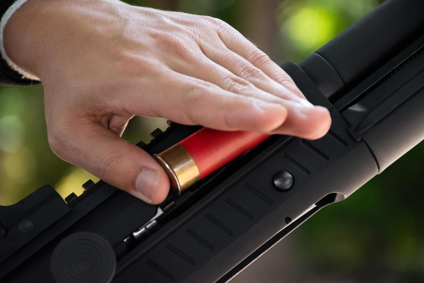 A shotgun shooter is loading a shot into the barrel of a long shotgun. photo