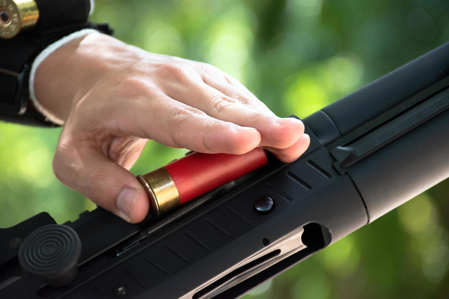 A shotgun shooter is loading a shot into the barrel of a long shotgun. photo