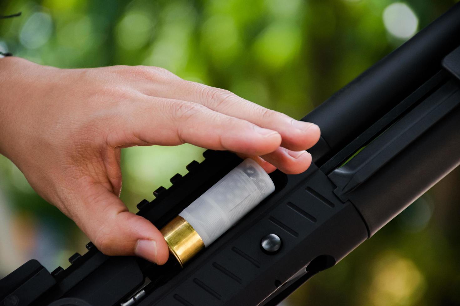 A shotgun shooter is loading a shot into the barrel of a long shotgun. photo