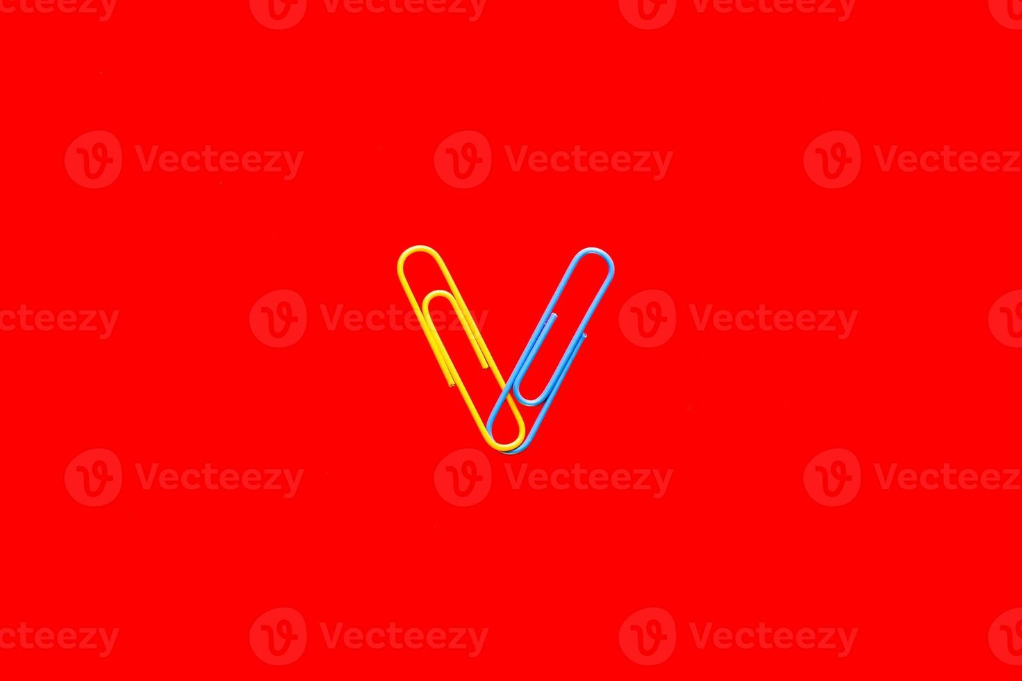 Yellow and blue paper clips on blood red background. photo