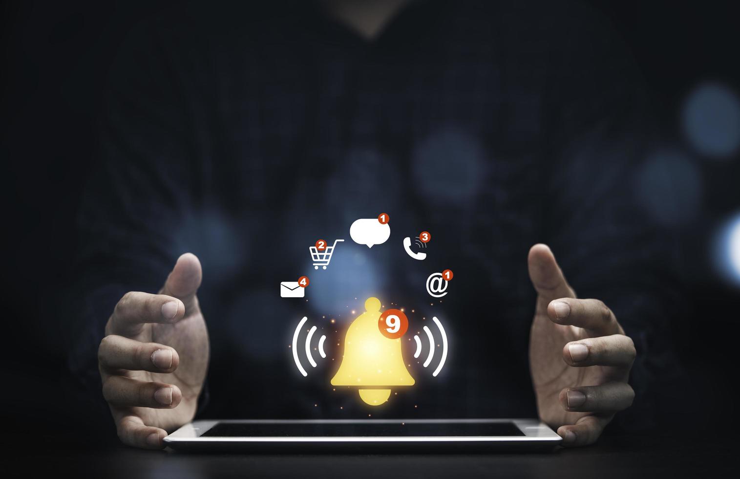 hombre de negocios que protege la tableta con el timbre virtual amarillo e iconos para el concepto de alerta de notificación de aplicación. foto
