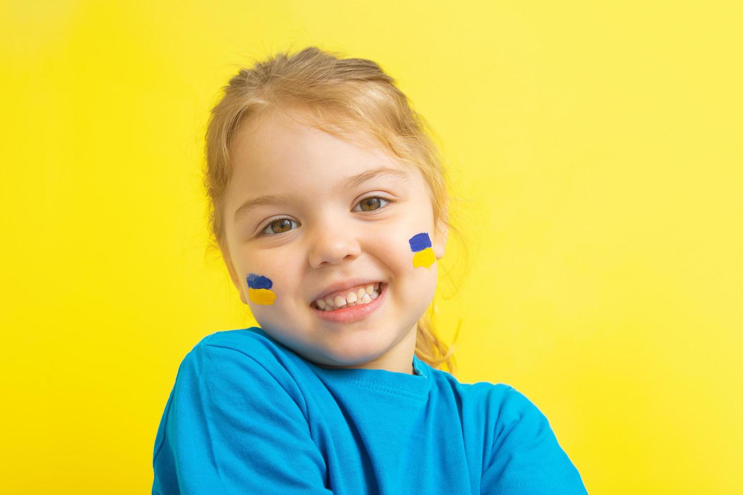 A girl with a painted Ukrainian flag of yellow and blue on her cheeks photo