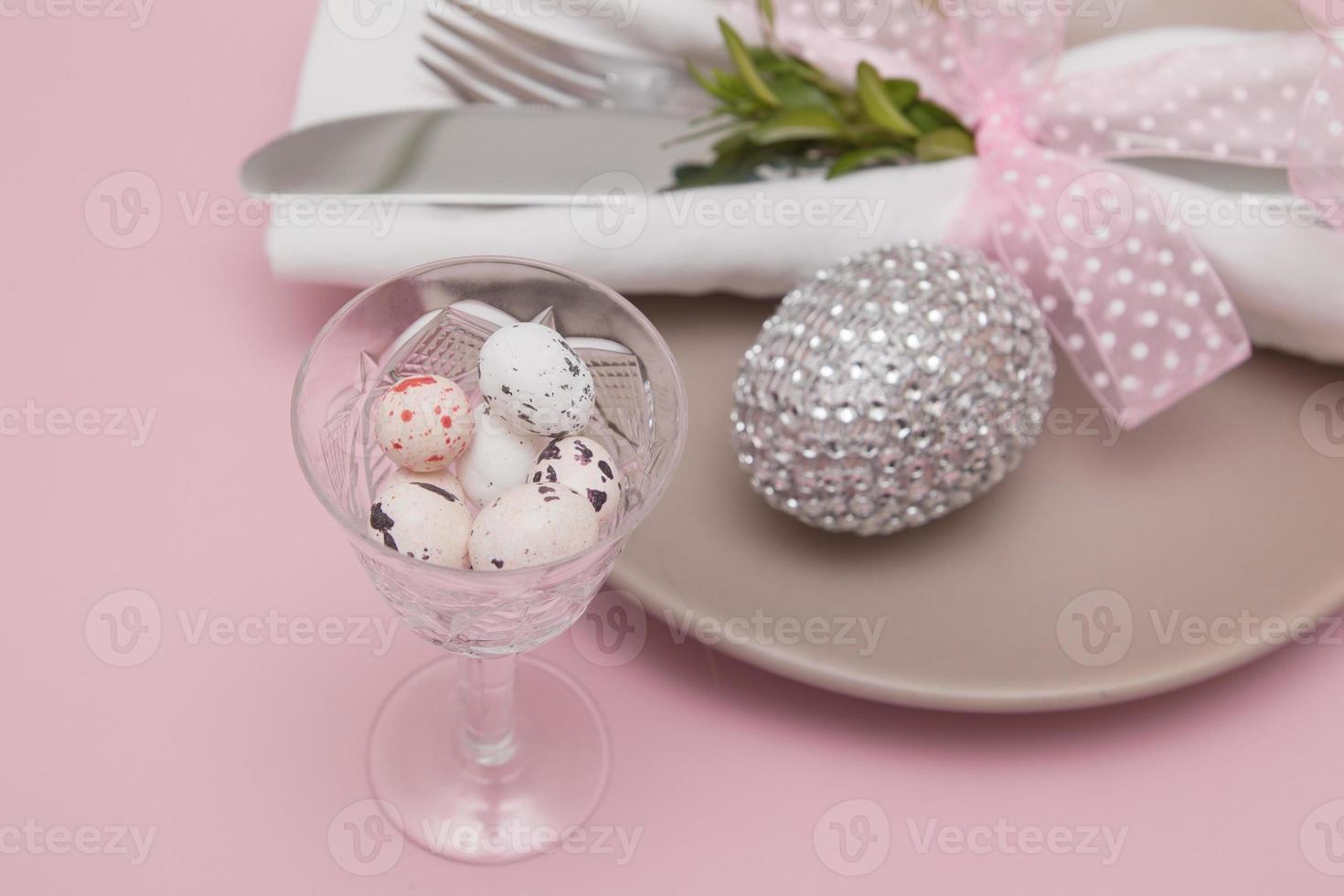 Glass with Easter eggs on the background of plates and cutlery. Variative focus photo