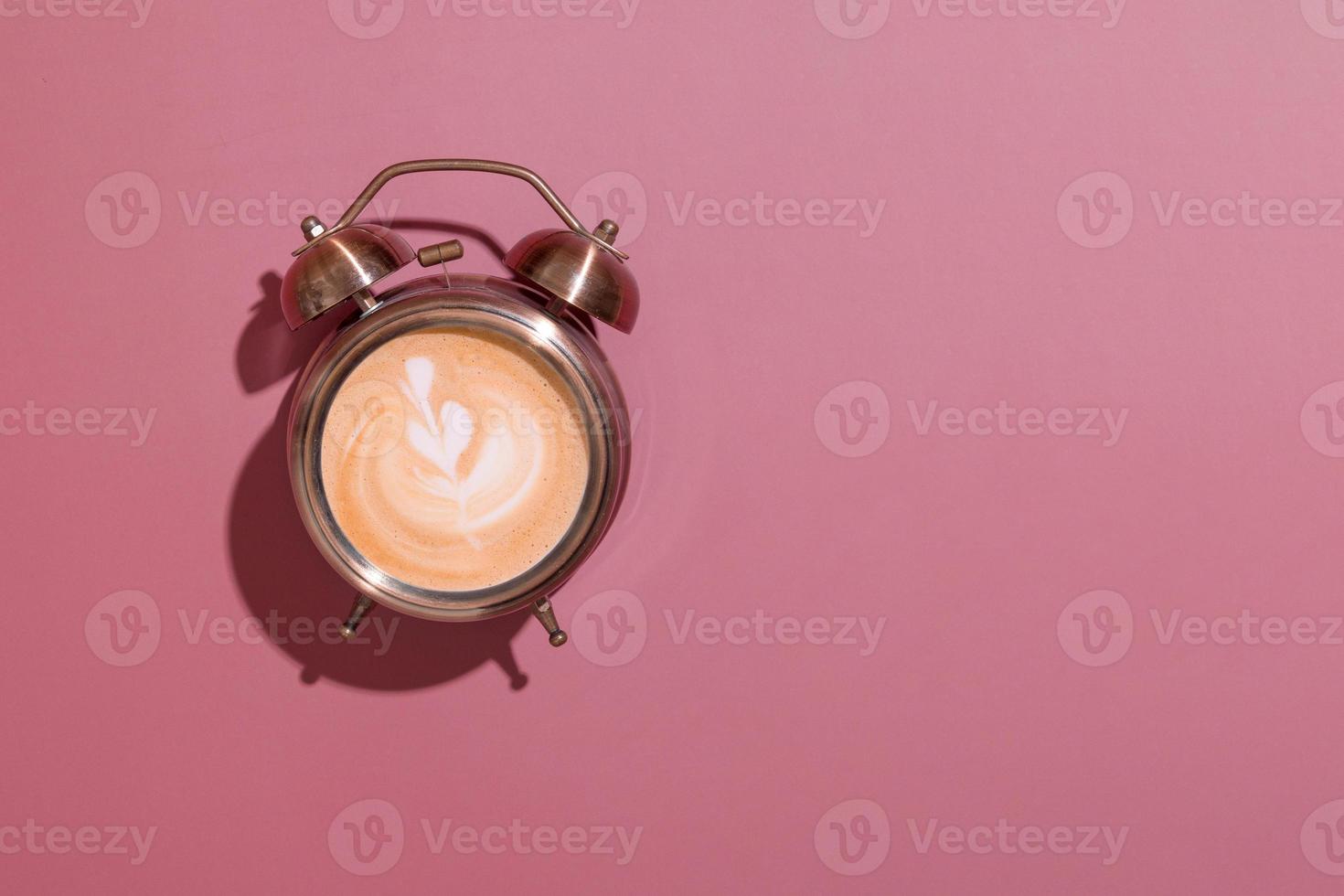 Alarm clock on with foamy coffee and pattern. Hard shadows. Morning rise with coffee for breakfast concept with copy space photo