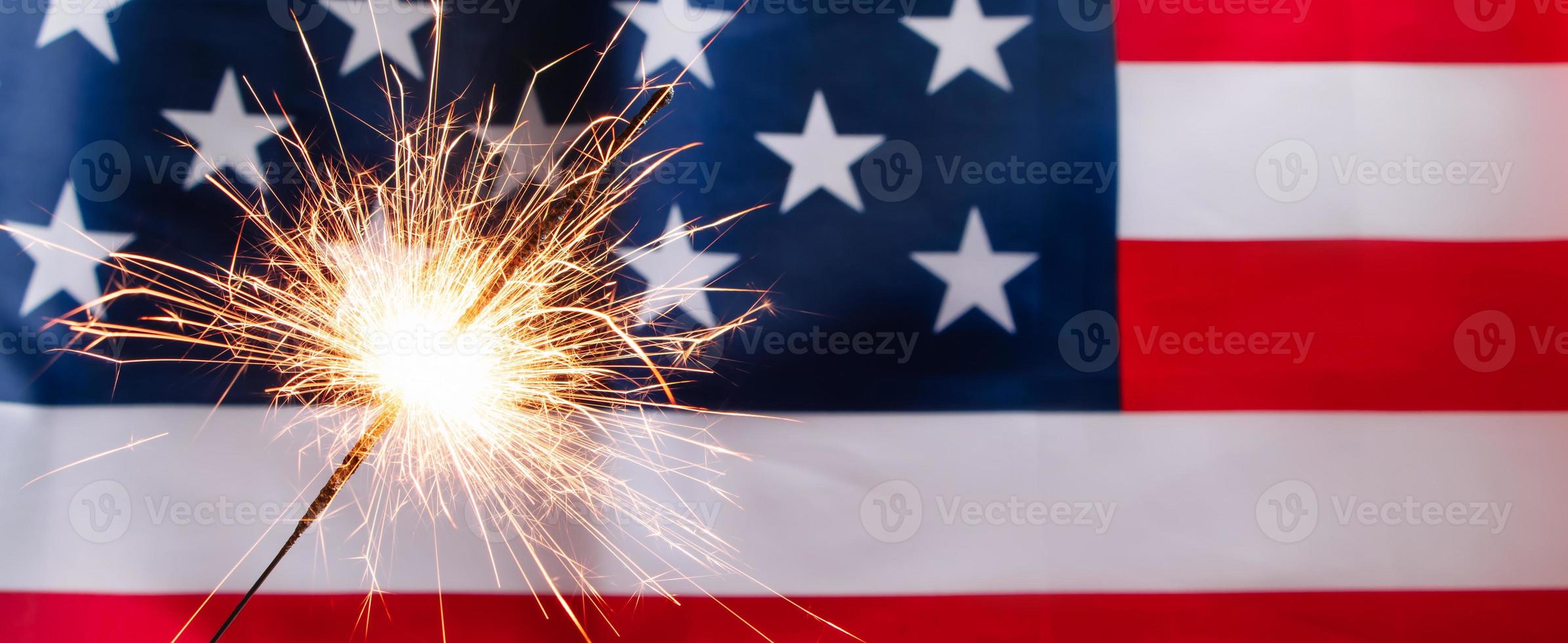 Concept for celebrating US Independence or Memorial Day. Sparkler on a background of American flag. photo
