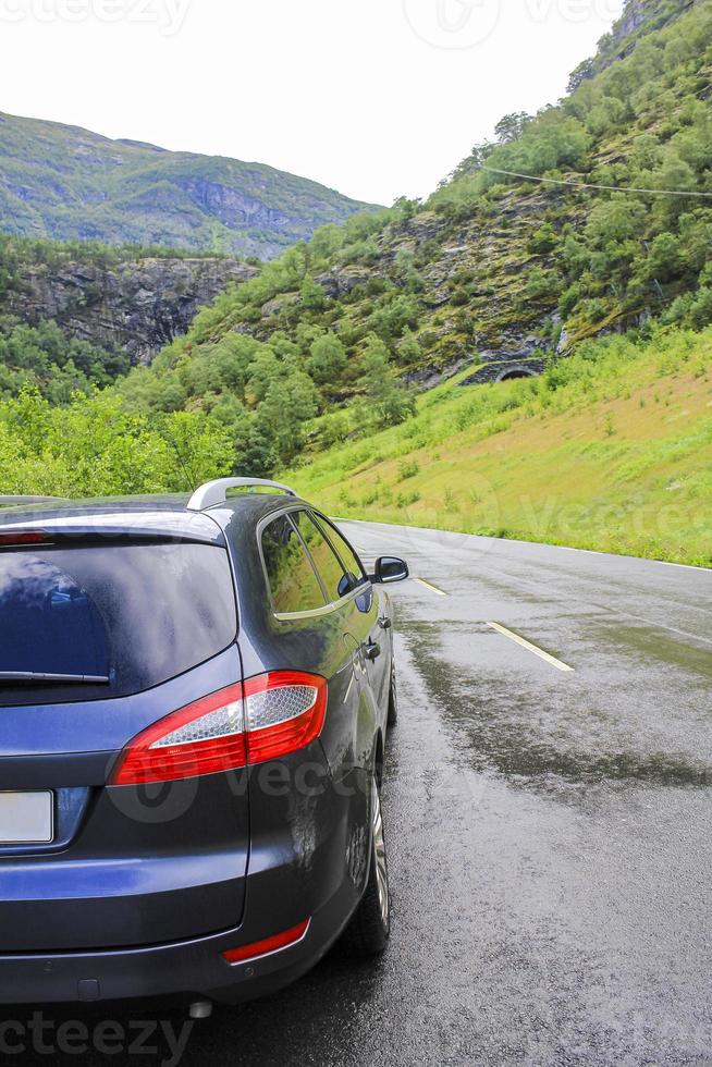 el coche conduce por una carretera mojada en las montañas, hemsedal, noruega. foto