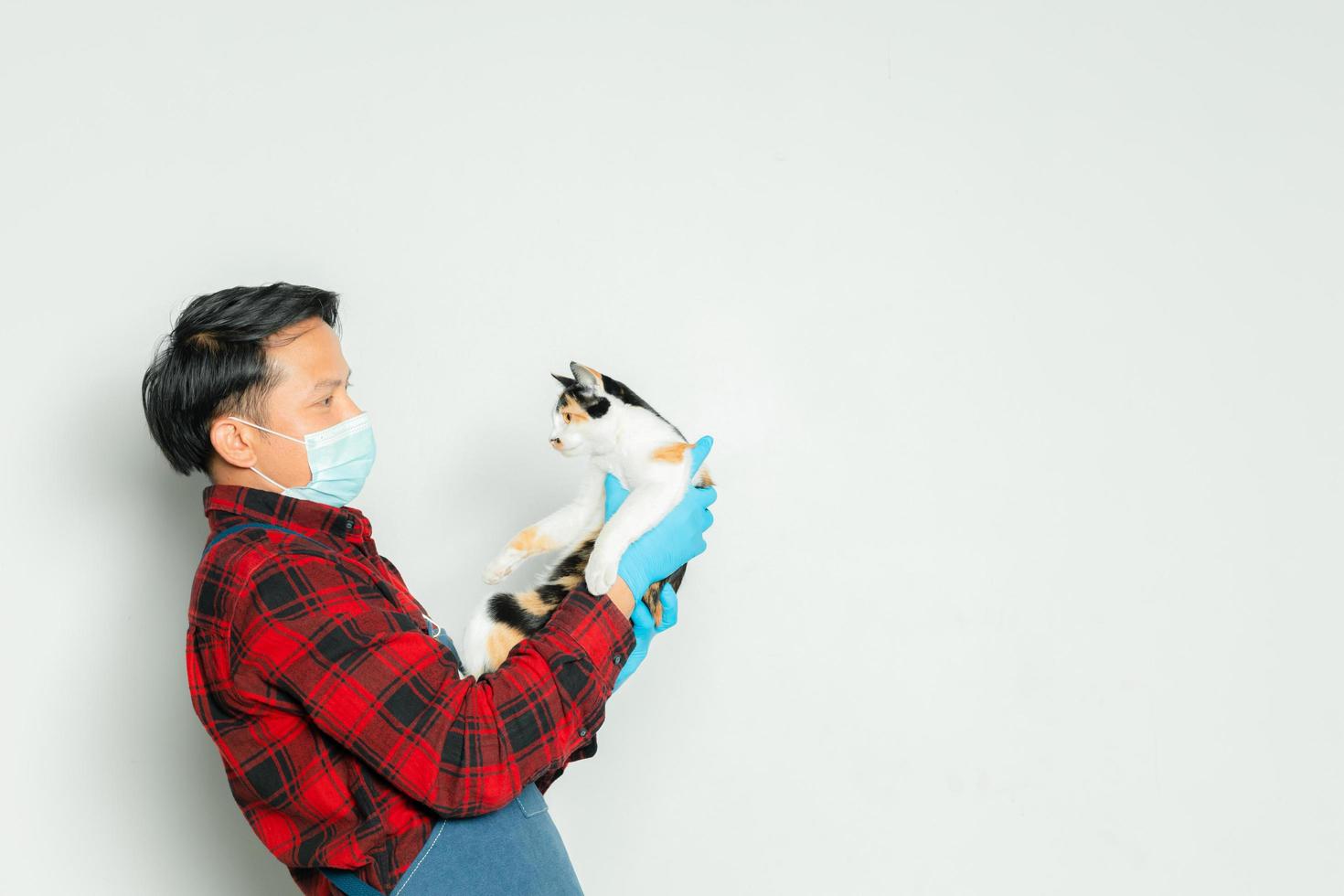 Pet owner affectionately holds a cat of 3 colors. photo