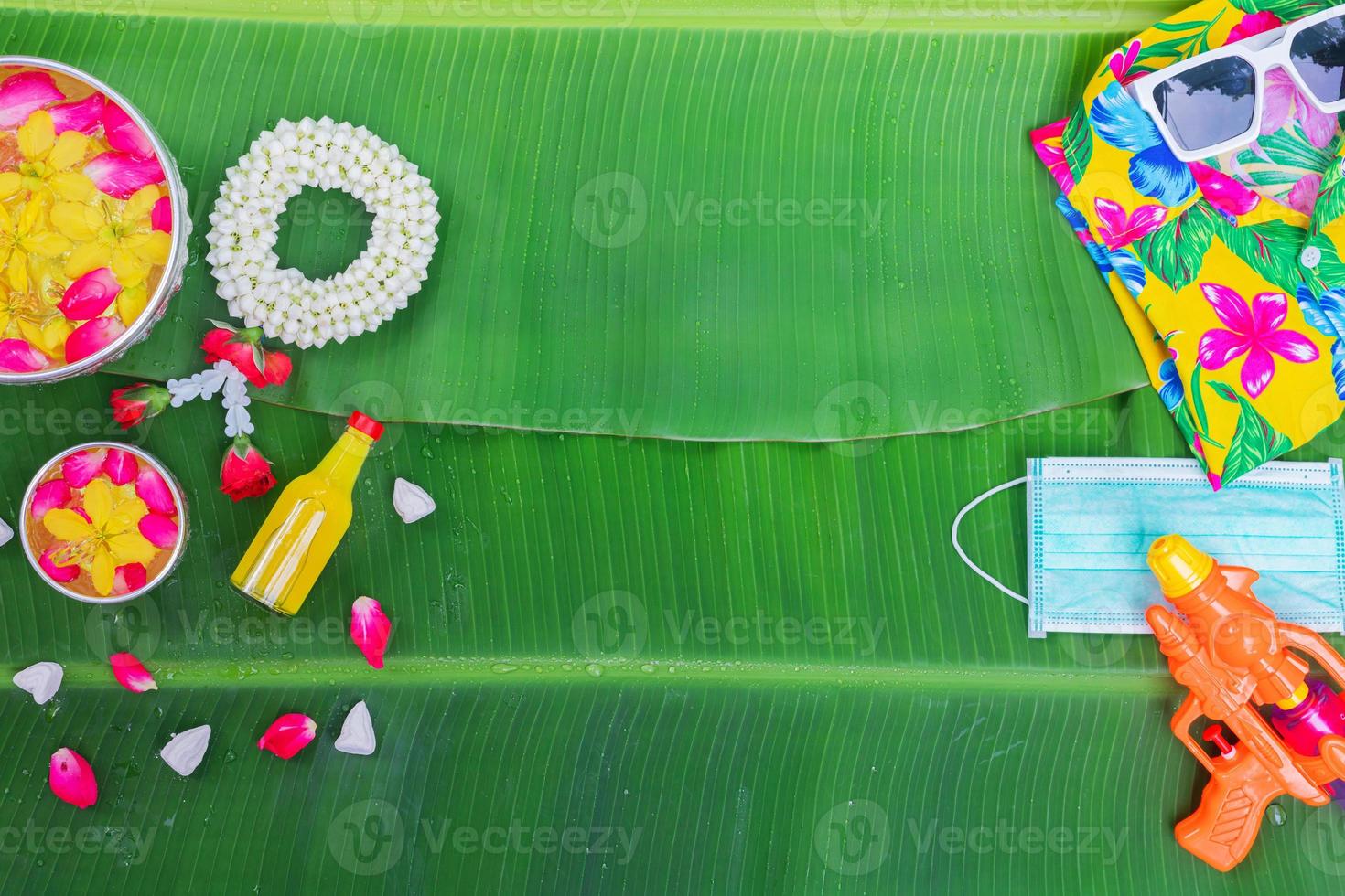 Songkran Festival background with jasmine garland Flowers in a bowl of water, perfume and limestone on a green wet banana leaf background. photo