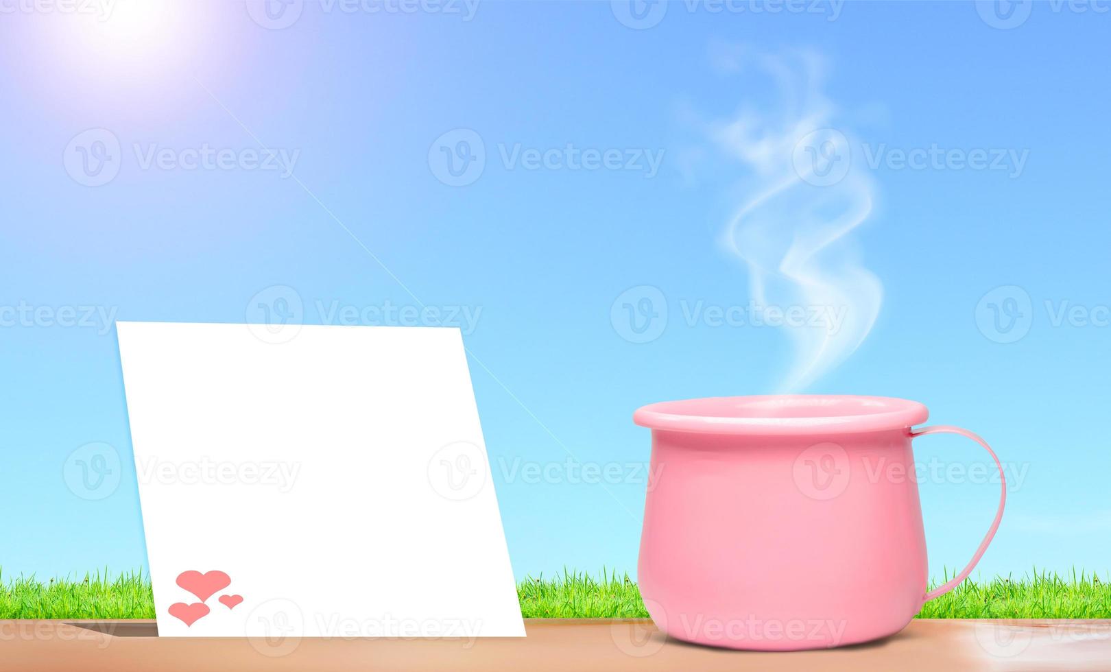 A bright pink metallic coffee cup on vacation.  And there is a blank sheet of note paper for inserting the contents. mock up and copy space photo