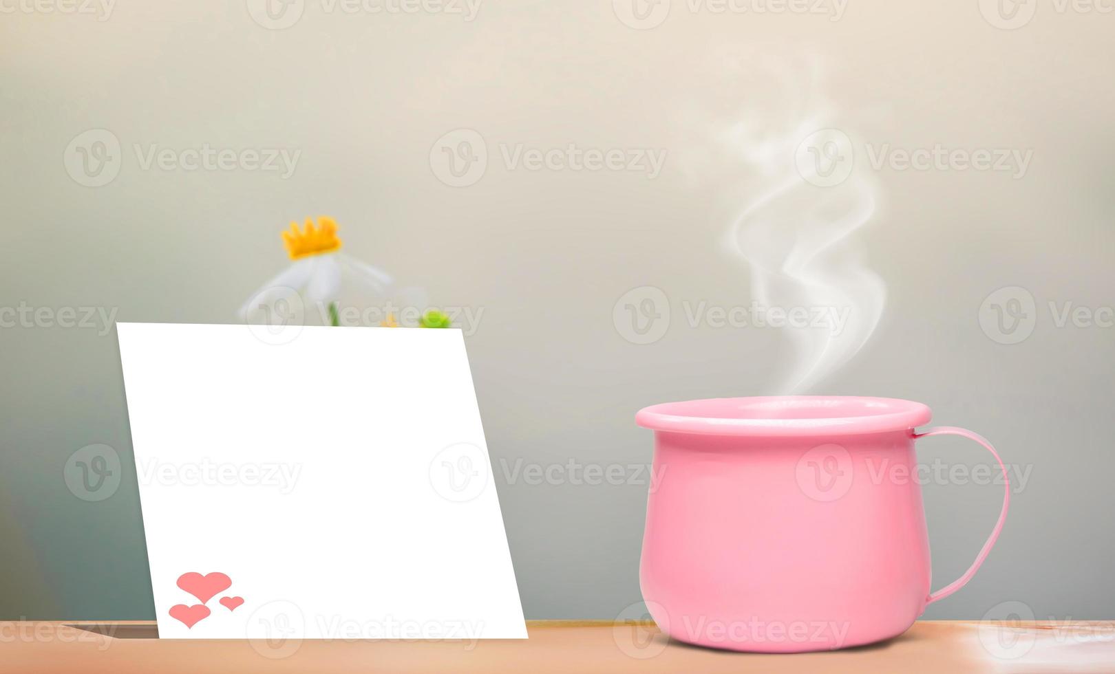A bright pink metallic coffee cup on vacation.  And there is a blank sheet of note paper for inserting the contents. mock up and copy space photo