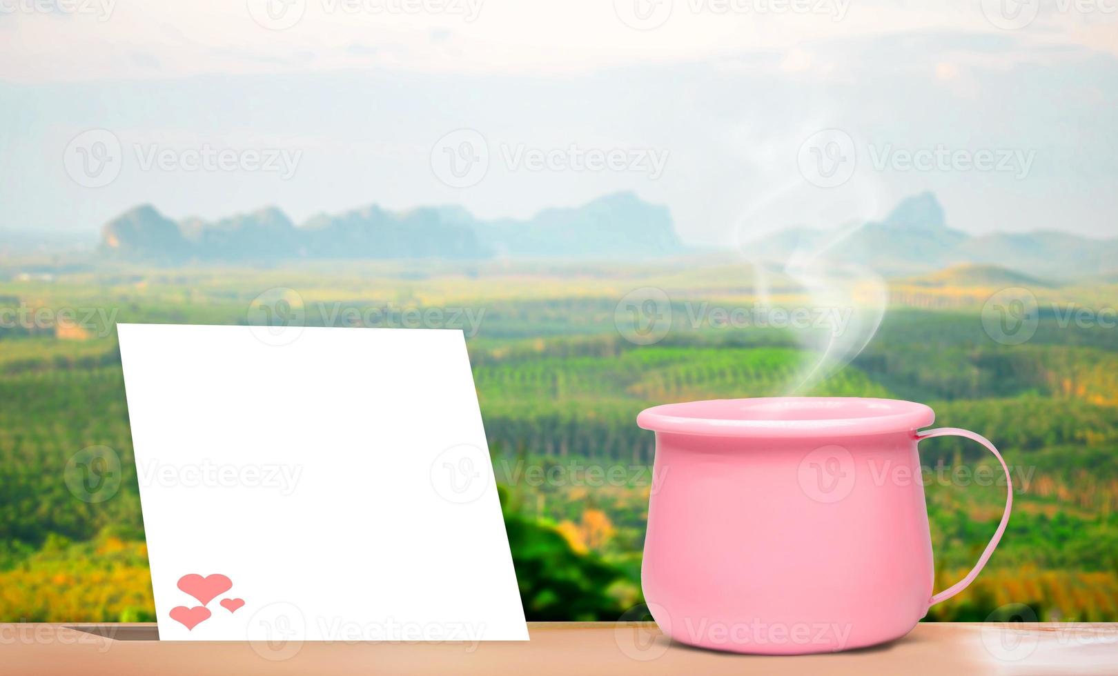 A bright pink metallic coffee cup on vacation.  And there is a blank sheet of note paper for inserting the contents. mock up and copy space photo