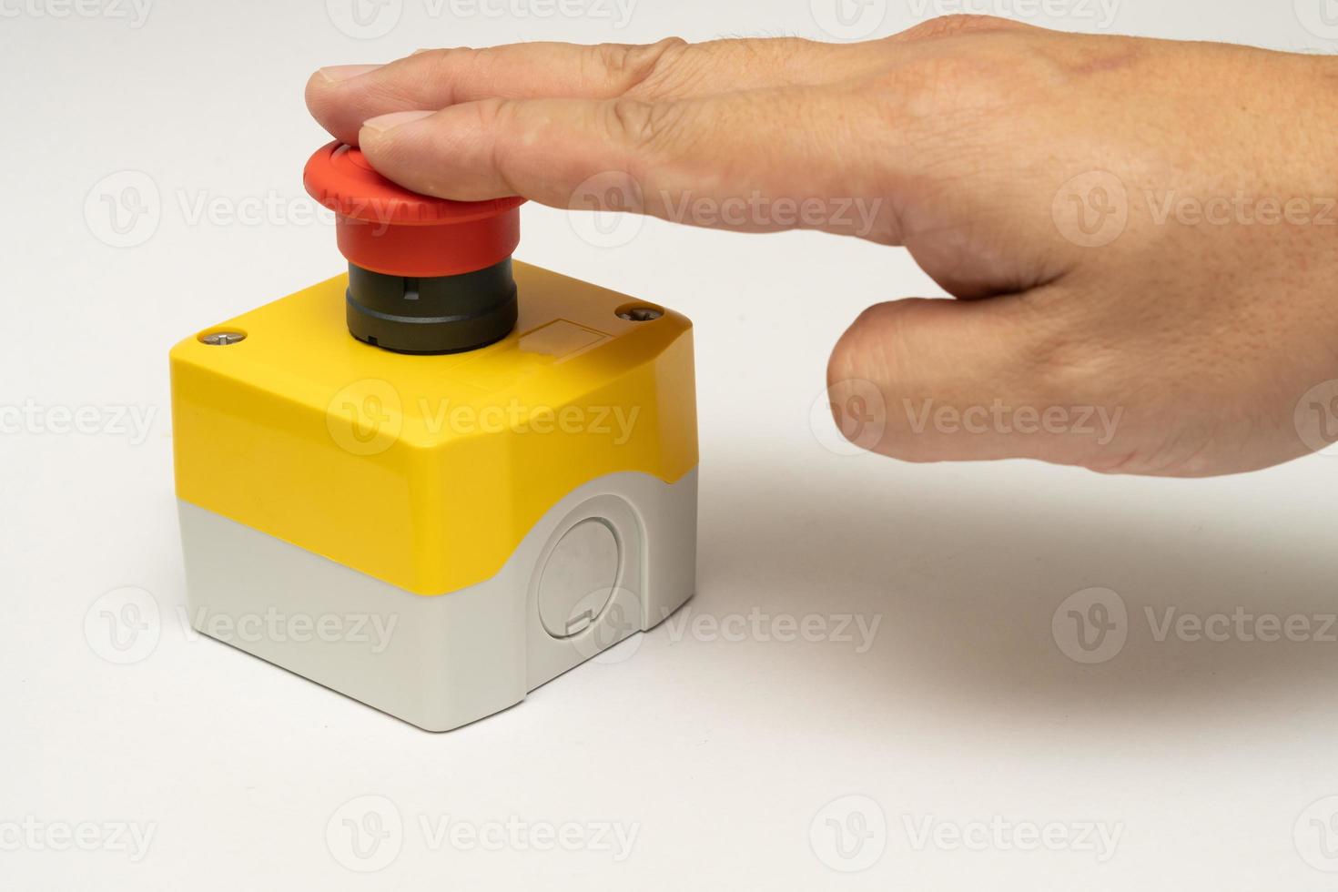 detener el botón rojo y la mano del trabajador a punto de presionarlo. botón de parada de emergencia. gran botón rojo de emergencia o botón de parada para presionar manualmente. foto