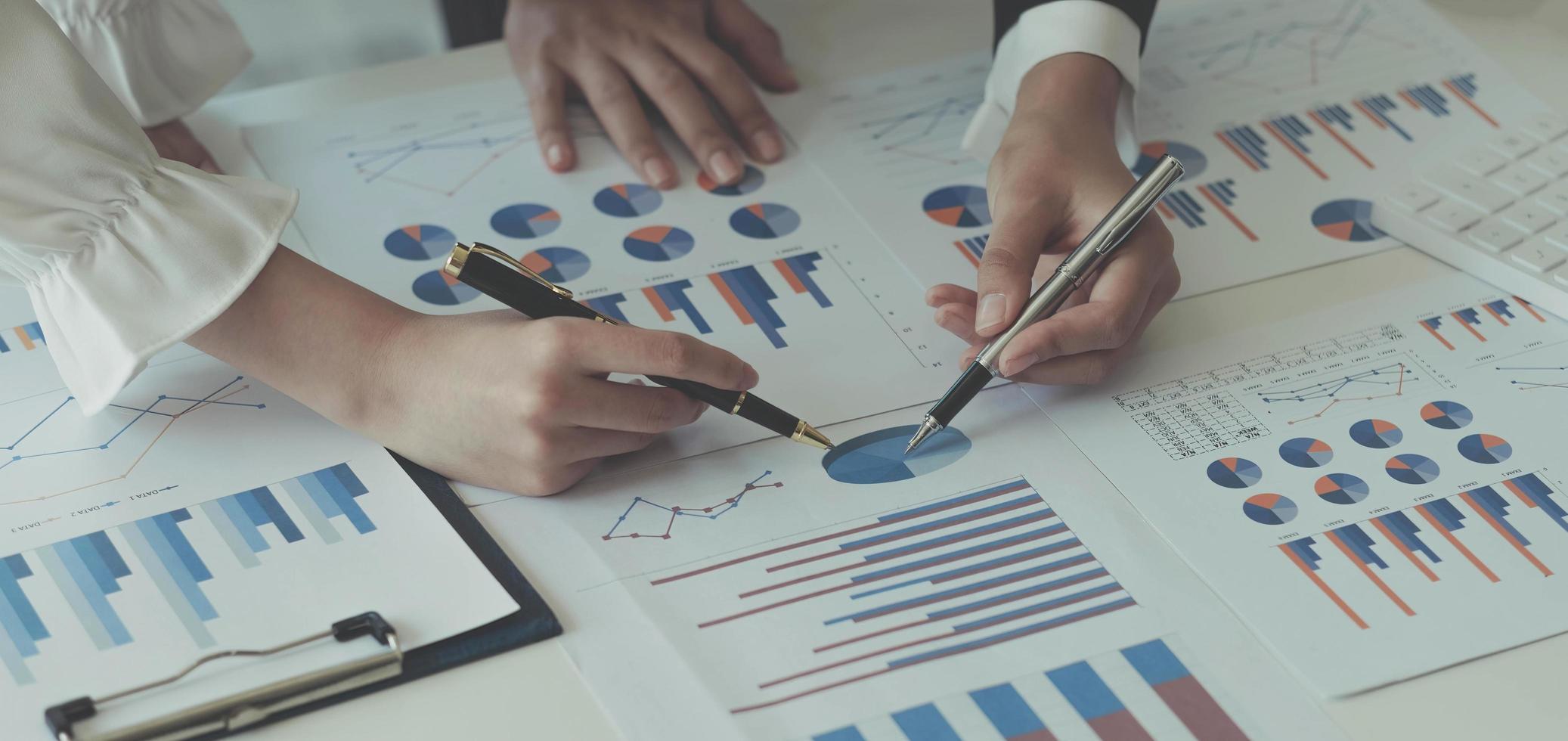 Close-up of two women's hands pointing to a turnover chart while talking on a wooden table in the office. group support concept photo