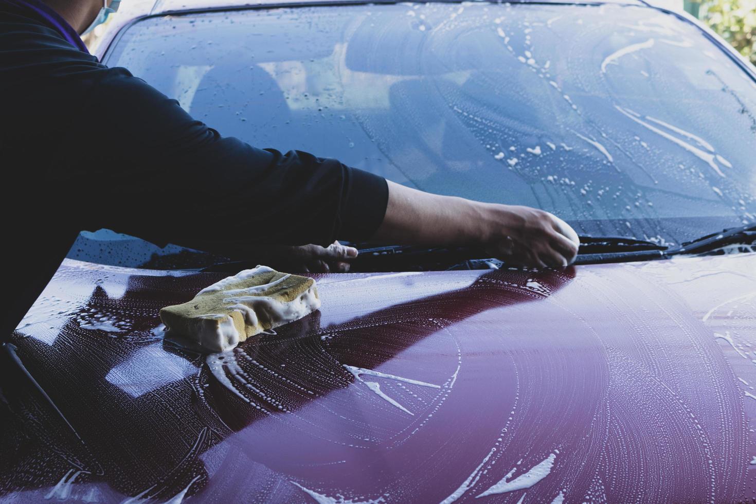 detalles del auto - el hombre sostiene la microfibra en la mano y pule el auto. enfoque selectivo. foto