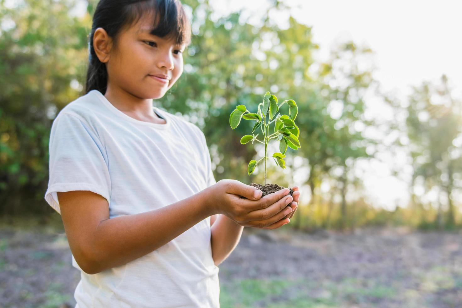 niños sosteniendo un árbol pequeño para plantar. concepto día de la tierra foto