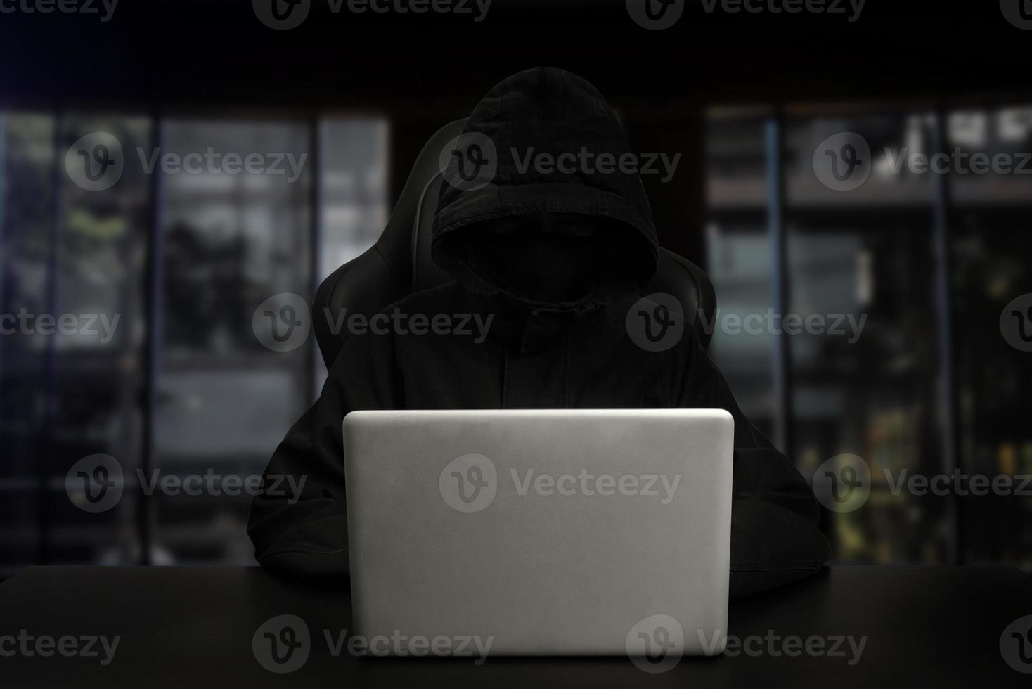 Hacker using computer with digital interface while sitting at desk of blurry interior. photo