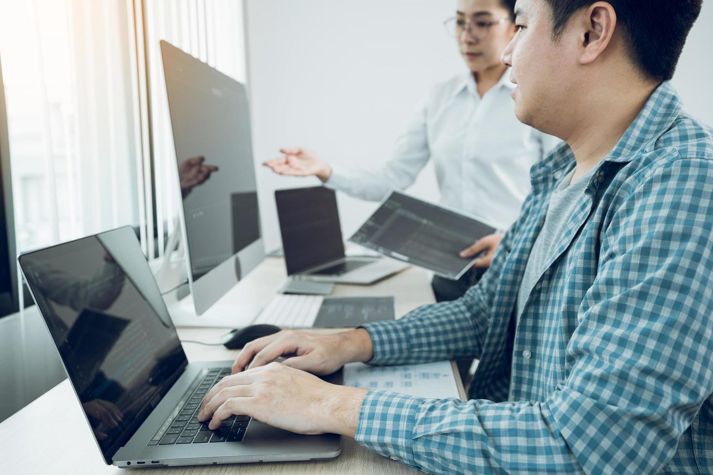 dos desarrolladores de software están analizando juntos el código escrito en el programa en la computadora en la sala de oficinas. foto