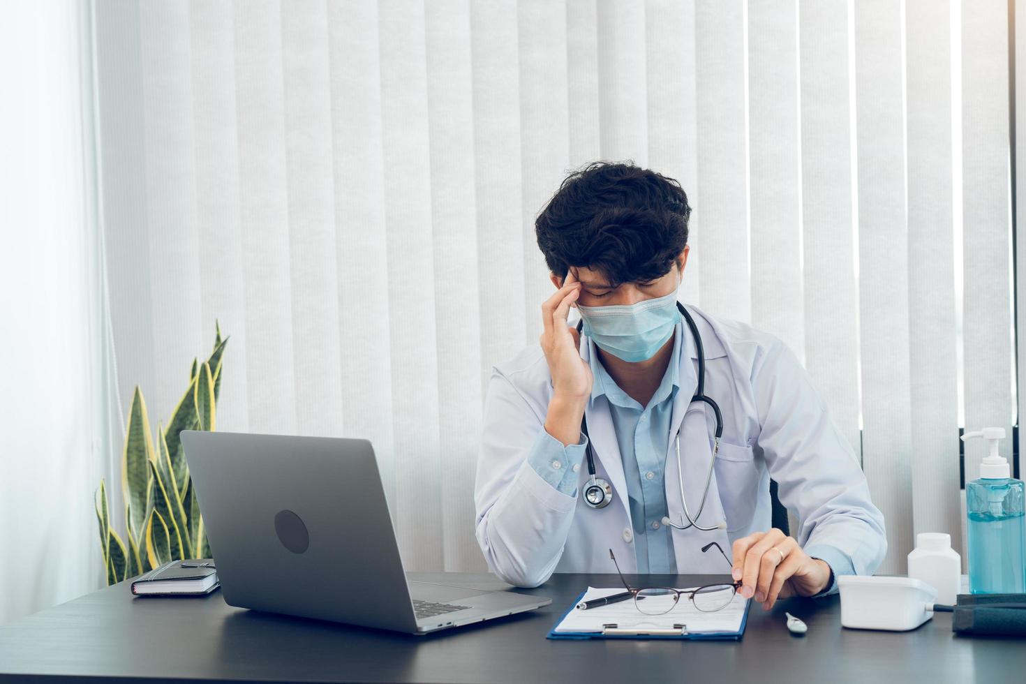 Asian young man doctor being exhausted and burnout in the office room. photo