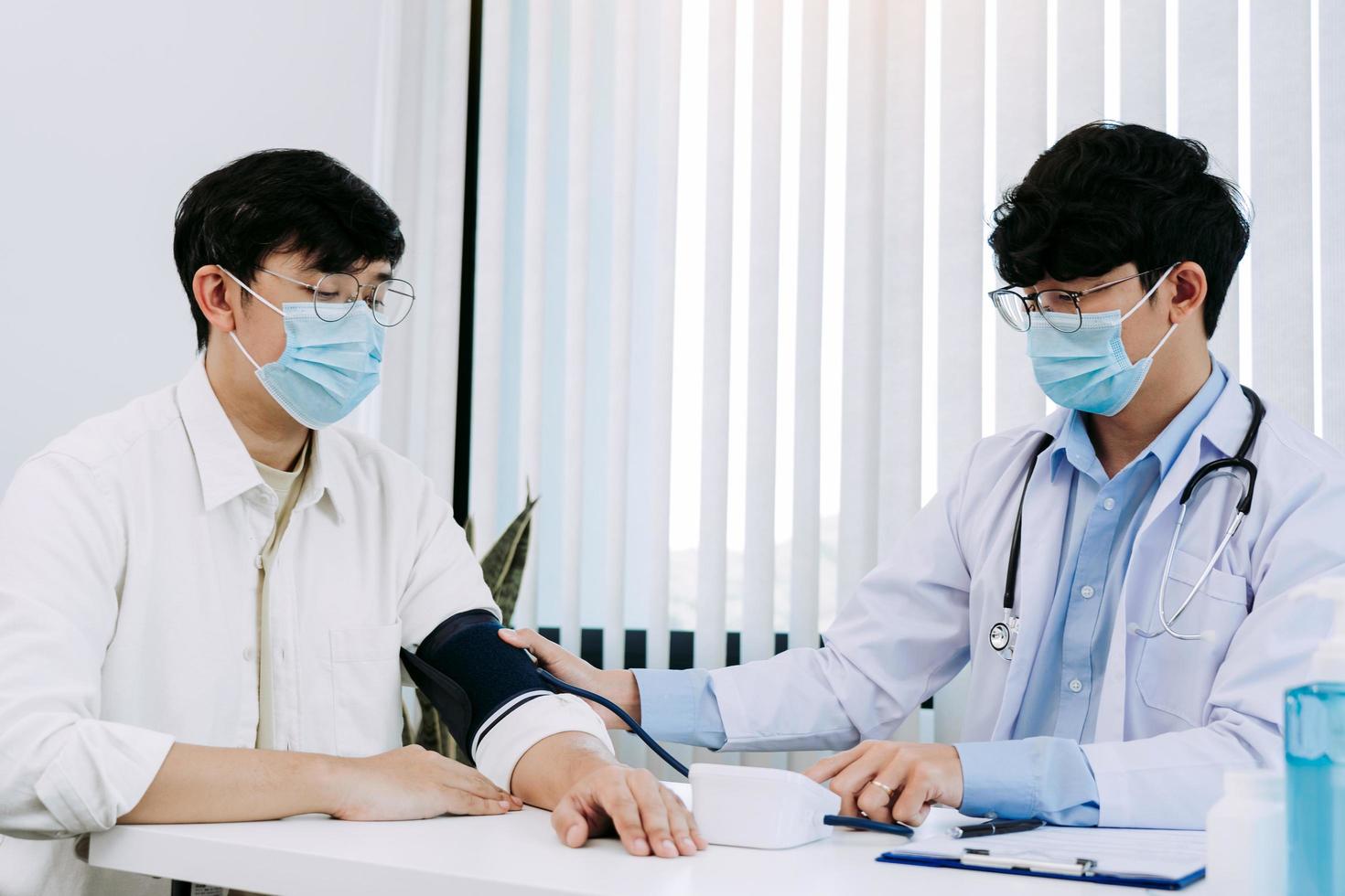Asian doctor is using a patient's blood pressure monitor at the time of his annual check-up and explains his blood pressure. photo