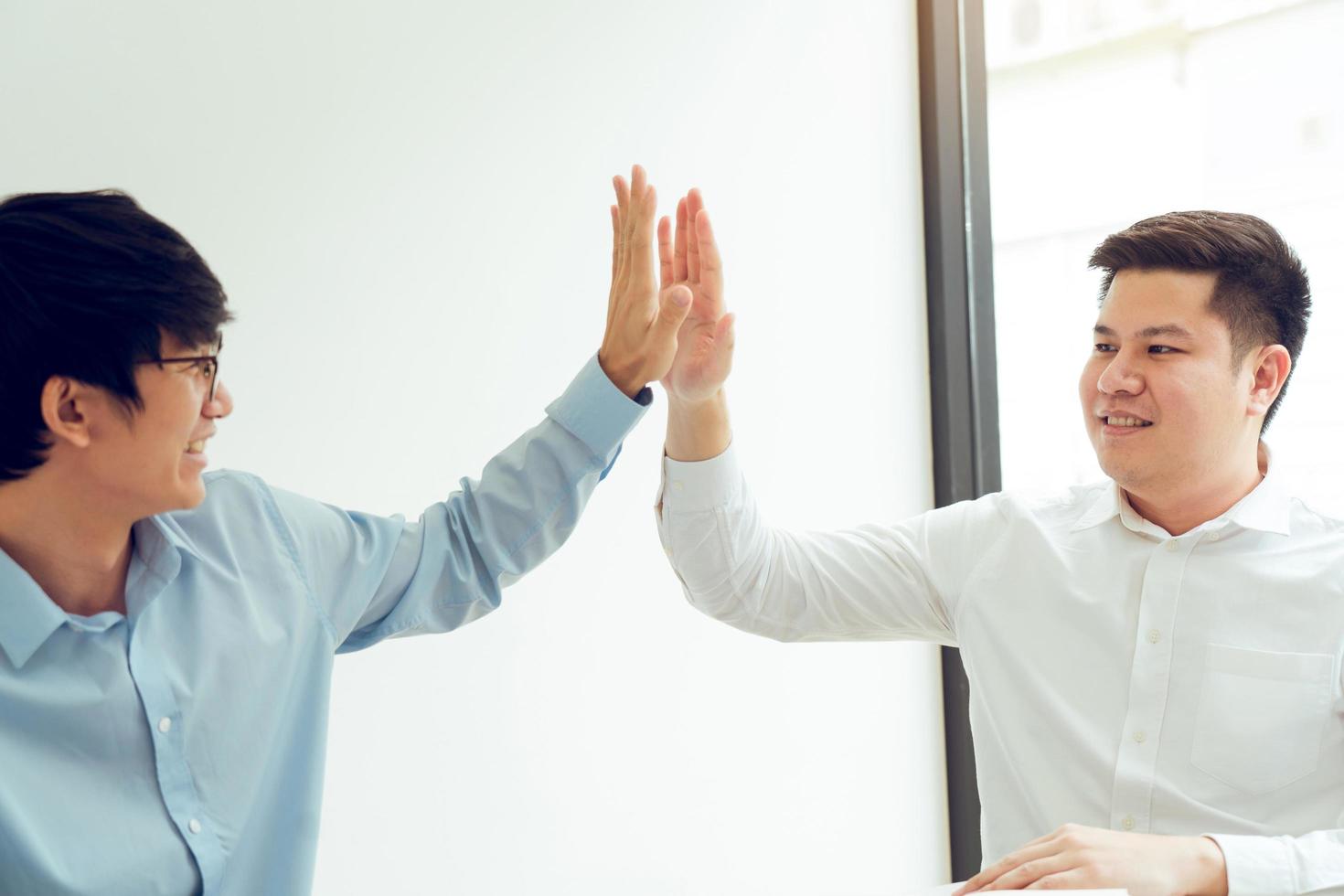 Two businessmen high five as they agree on the company's budget. photo