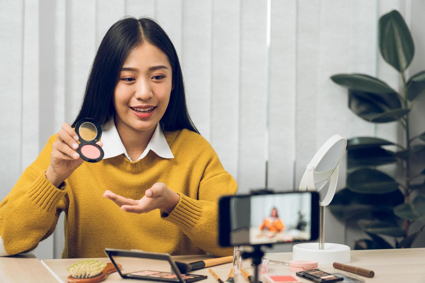 Young Asian beauty blogger is showcasing cosmetic products as well as tutorials on how to apply and record makeup tutorials on social media networks. photo