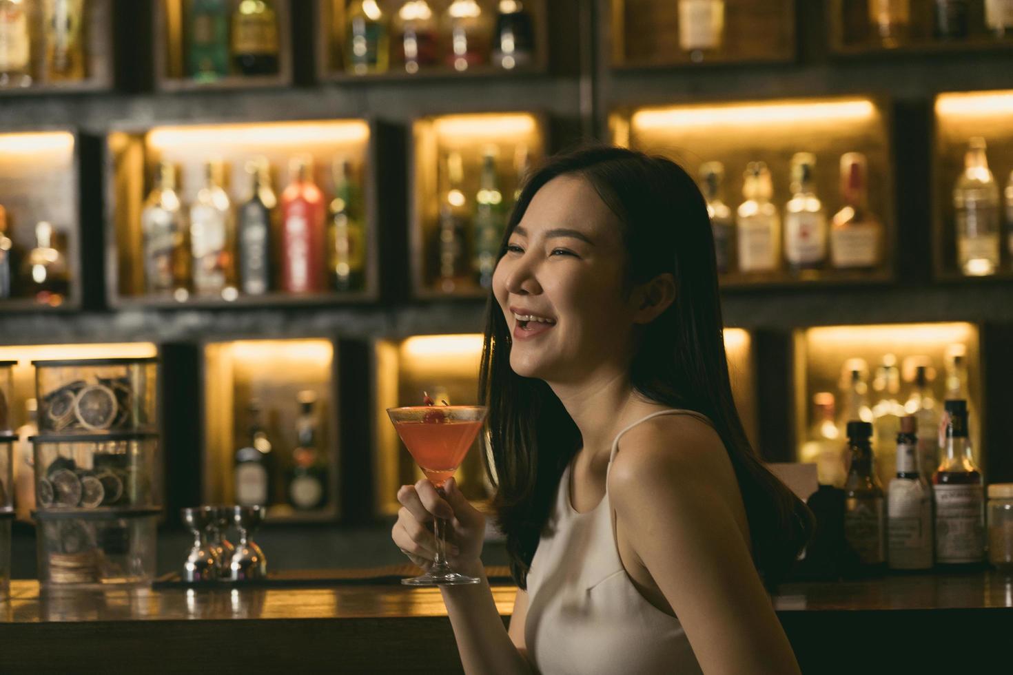 Asian women drinking cocktails and having fun at the bar at night. photo