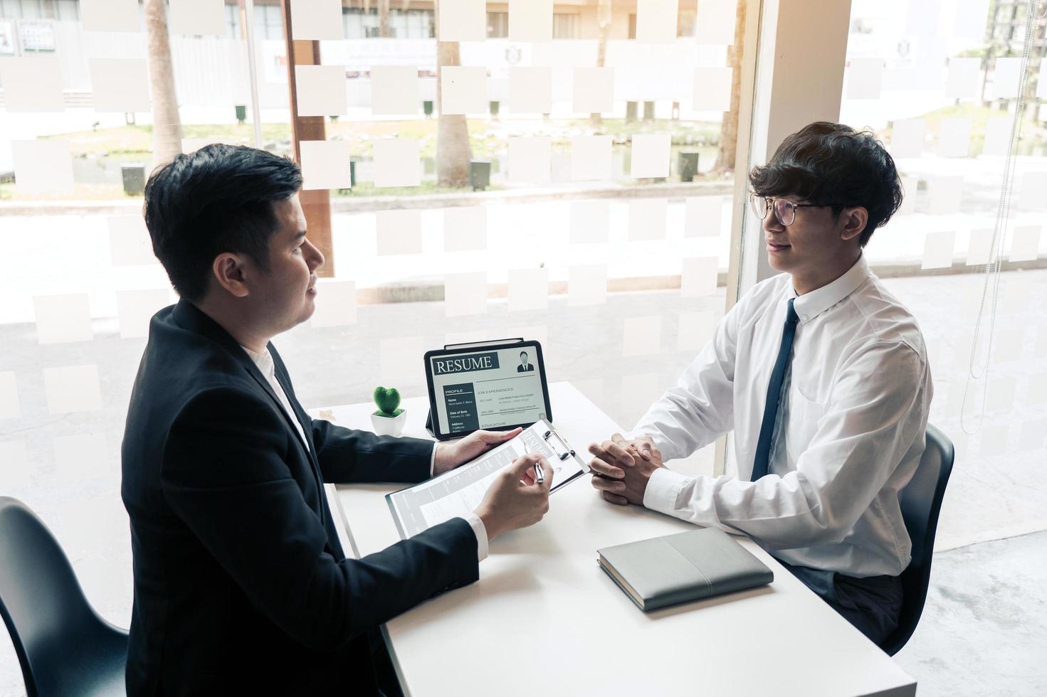 Asian young adult sitting at desk across from manager being interviewed job interview in business room. photo