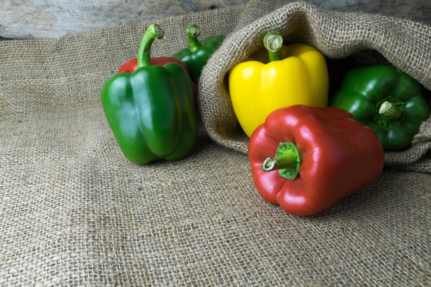 Colored bell peppers on wooden table photo