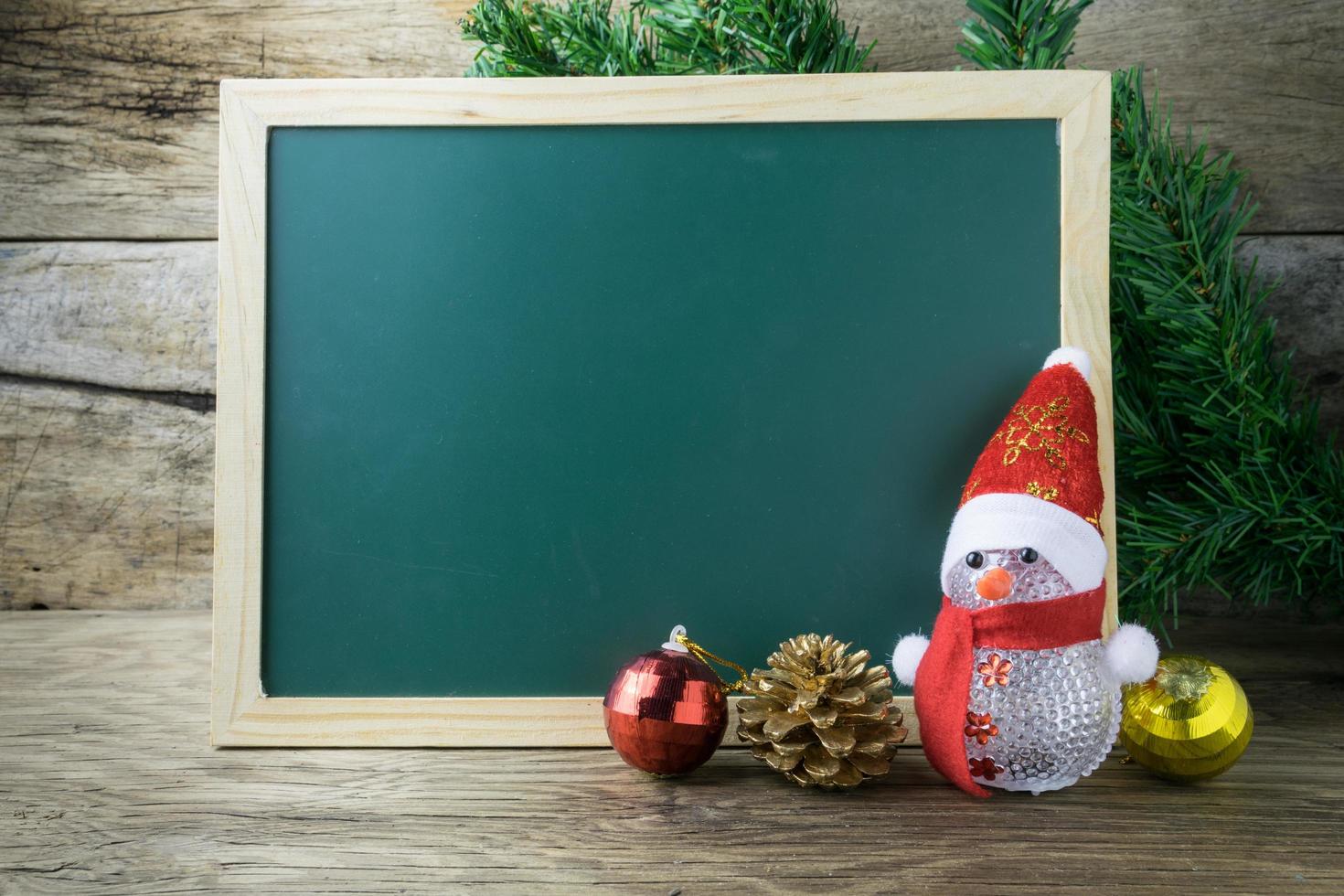 Blackboard With Red Santa Hat And Christmas snowman toy on old wooden background. photo
