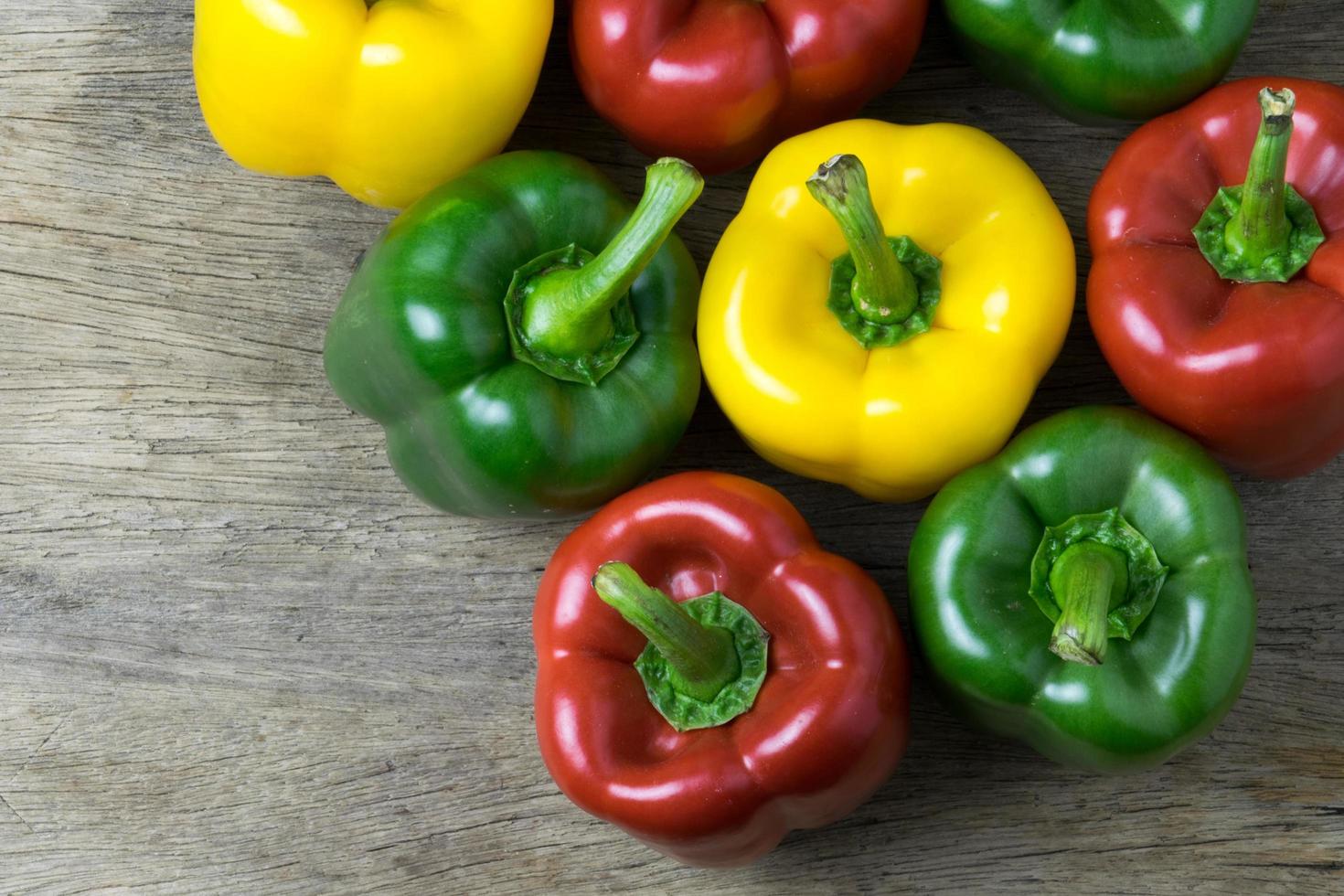 Colored bell peppers on wooden table photo