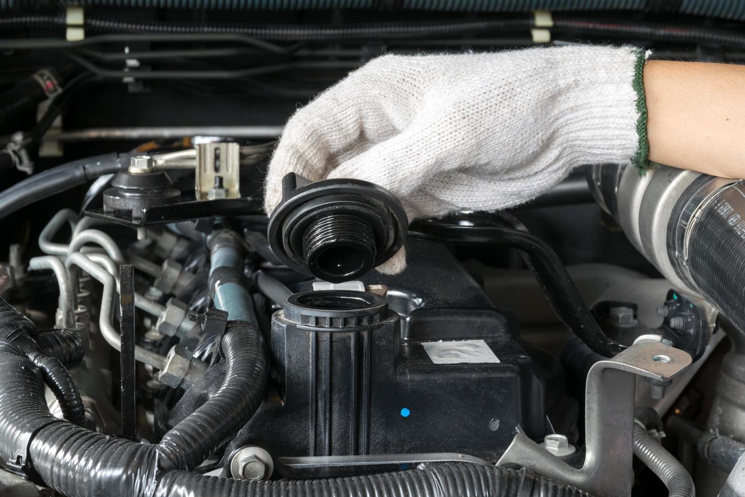 A mechanic is opening the oil cap from a car engine. photo