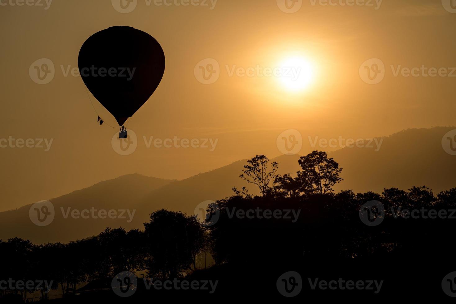 la silueta del globo aerostático volando en el cielo durante la vista del atardecer. foto