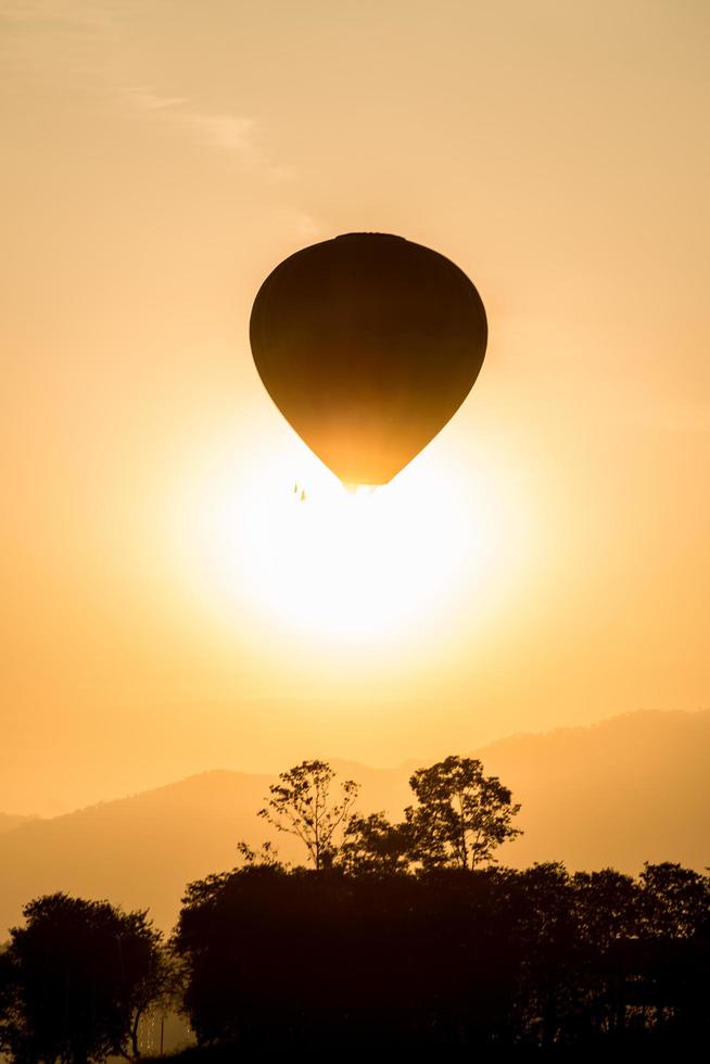 The silhouette of hot air balloon flying up in the sky during sunset view. photo