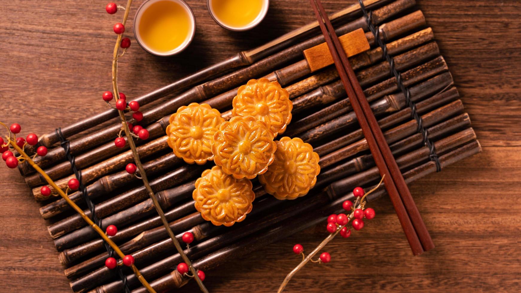 Chinese traditional pastry Moon cake Mooncake with tea cups on bamboo serving tray on wooden background for Mid-Autumn Festival, top view, flat lay. photo