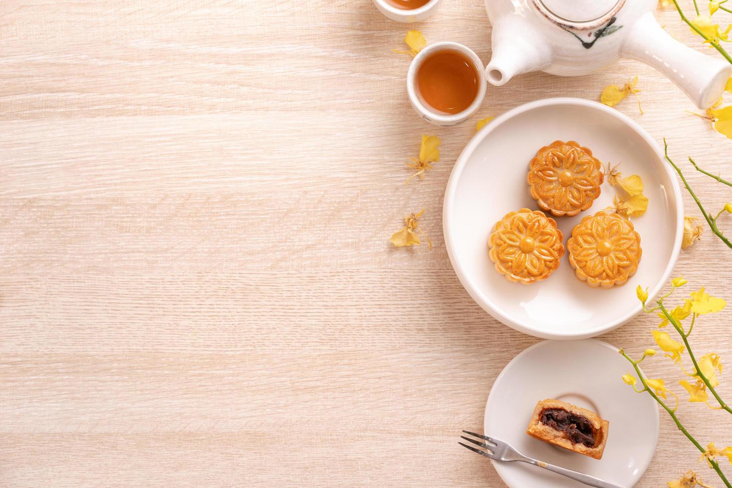Delicious moon cake for Mid-Autumn festival with beautiful pattern, decorated with yellow flowers and tea. Concept of festive afternoon pastry design photo