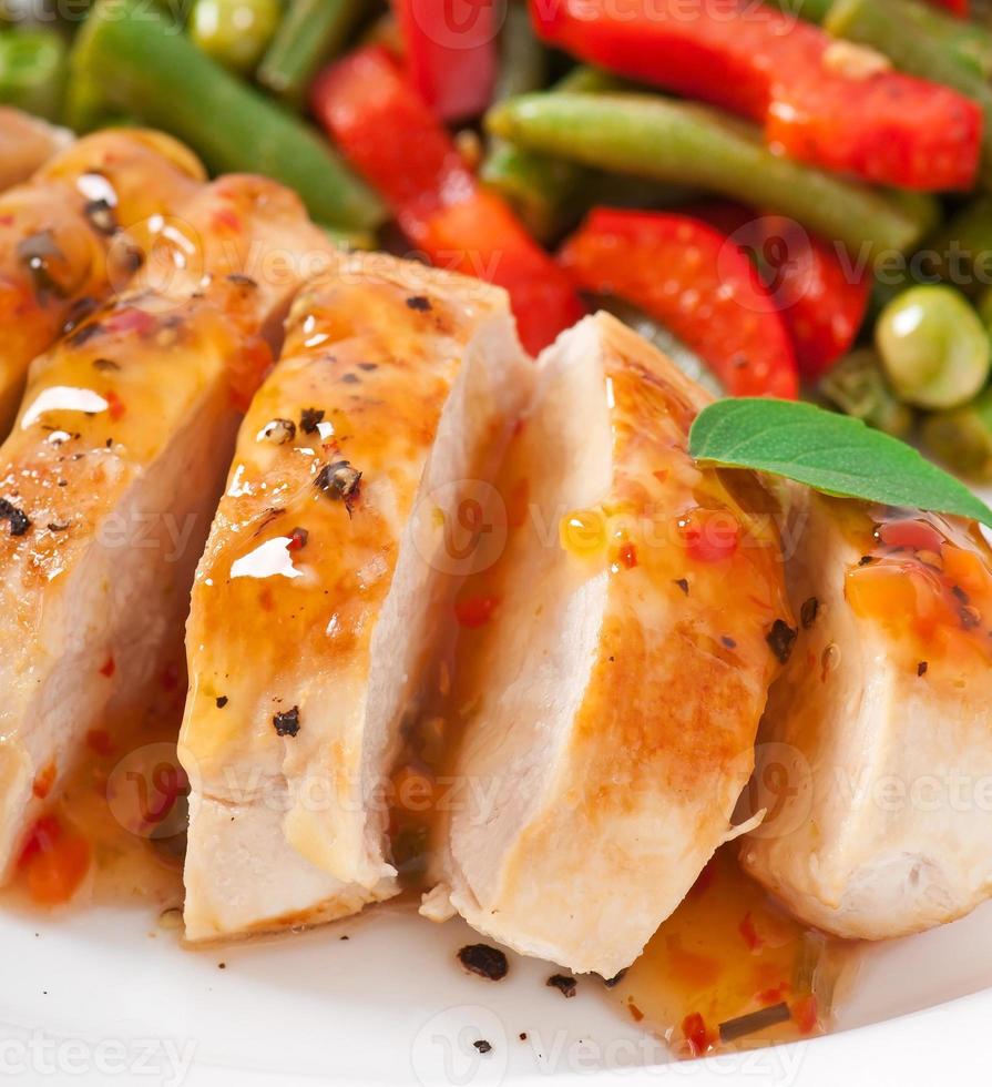 Chicken breast with vegetables and sauce decorated with basil leaves photo