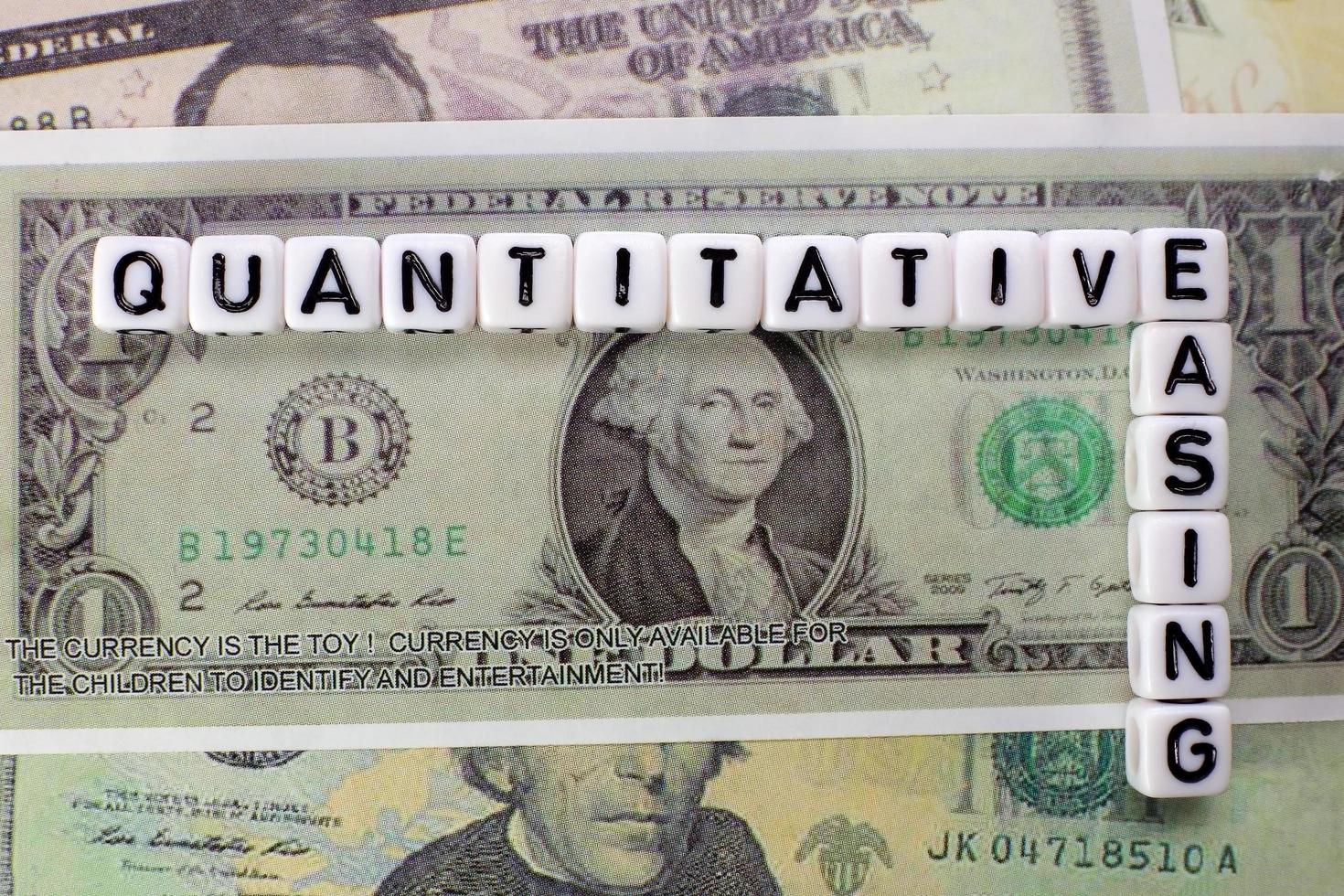 Quantitative Easing written on white cube with dollars background for QE concept. photo